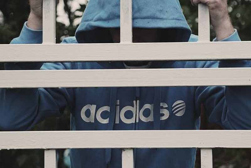 Man with a blue Adidas hoodie holding a white grill