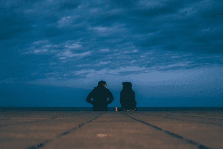 A couple talking by the sea in the night